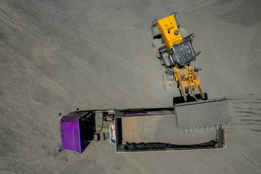 Kum yükleyicileri çöp kamyonlarına taş topluyor.