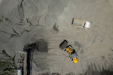 Kum yükleyicileri çöp kamyonlarına taş topluyor.