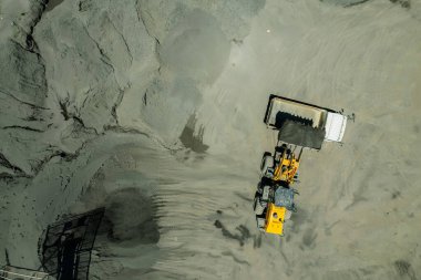 Kum yükleyicileri çöp kamyonlarına taş topluyor.