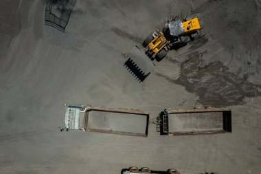 Kum yükleyicileri çöp kamyonlarına taş topluyor.