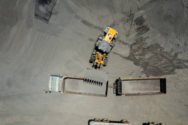 Kum yükleyicileri çöp kamyonlarına taş topluyor.