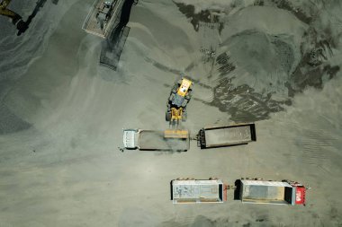 Kum yükleyicileri çöp kamyonlarına taş topluyor.