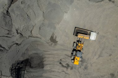 Kum yükleyicileri çöp kamyonlarına taş topluyor.