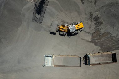 Kum yükleyicileri çöp kamyonlarına taş topluyor.