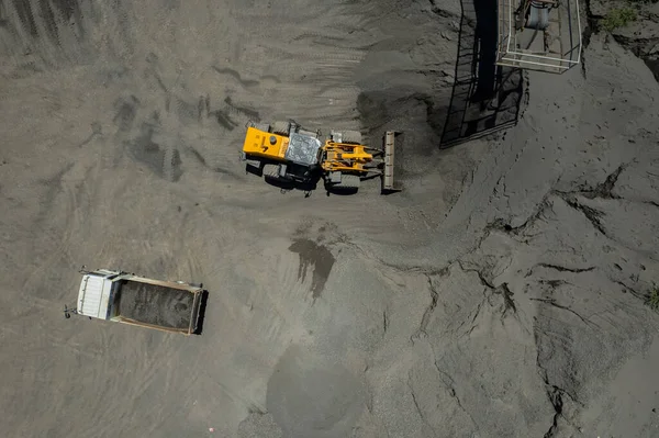 Kum yükleyicileri çöp kamyonlarına taş topluyor.