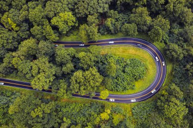 Road, highway or freeway. Road with traffic. Highway for cars and trucks. Roadway with yellow double solid line. Country road in the green forest. Scenic aerial top view. North Carolina mountains
