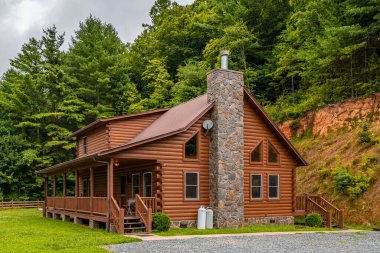 Log cabin. Wooden home. House exterior. Log cabin in Great Smoky Mountains North Carolina. Scenic view. Great for vacation. Country landscape with cottage. Green forest on background. Pine trees.