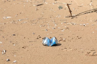 Kumsaldaki damlalar yüzünden bozulmuş teneke kutu. Çevre kirliliği, kumsalda buruşmuş teneke kutu..