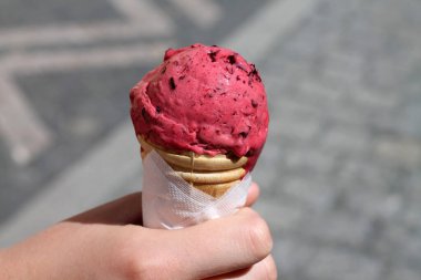 Ice Cream Cone In Hand. Pink frozen berry dessert.