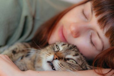 Kadın kucağında kediyle yatıyor. Yakın plan..