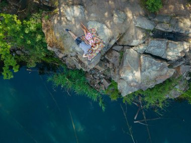 Kariyer. Bir adam ve bir kadın gölü olan bir kayanın üzerinde yatıyor. Hava görünümü.