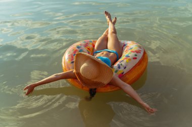 Dinlen. Bir kadın gölde şişme bir yüzüğün üzerinde yüzüyor..