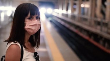 Salgın hastalık. Koruyucu maskeli bir kadın metroda tren bekliyor..