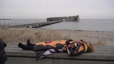 Fatigue. The woman was tired and lay down on a bench to rest.