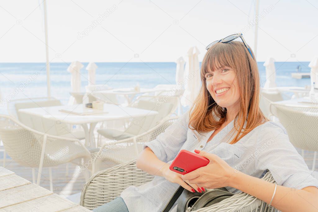 Portrait. A woman is sitting in a cafe with a mobile phone.
