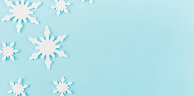 Noel kompozisyonu. Mavi arka planda kar tanelerinden yapılmış bir pankart. Noel, kış, yeni yıl konsepti. Asgari düzeyde. Düz konum, üst görünüm, kopyalama alanı