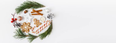 Moda yaratıcı Noel Afişi. Kış, yeni yıl kompozisyonu. Çam ağacı dalları, beyaz arka planda Noel süslemeleri. Düz yatış, üst görünüm