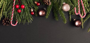 Dekorasyon ve siyah arkaplandaki Xmas ağaç dallarından yapılmış Noel Afişi. Yeni yıl tebrik kartı. uzanma, üst görünüm, kopyalama alanı