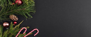 Dekorasyon ve siyah arkaplandaki Xmas ağaç dallarından yapılmış Noel Afişi. Yeni yıl tebrik kartı. uzanma, üst görünüm, kopyalama alanı