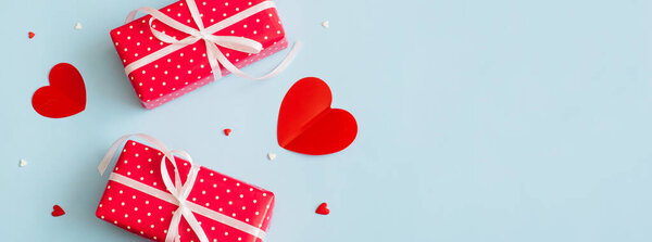 Banner Valentines Day background February 14th. Gifts, confetti, red hearts of paper on pastel blue background. Valentines day concept. Flat lay, top view, copy space