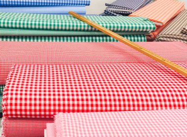 Kumaş dükkanında satılık bir masanın üzerinde farklı renklerde kumaşlar var. Dükkanda çok renkli kumaşların tam çerçeve görüntüsü.