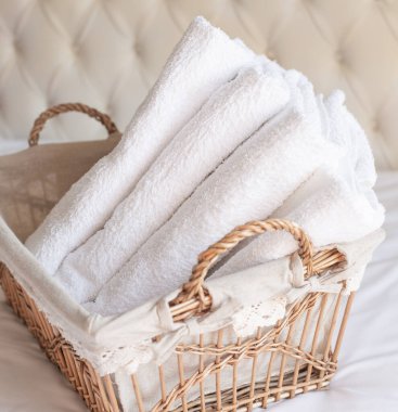 Beyaz arka planda hasır bir sepetin içinde dört beyaz havlu var. Retro tarzı. Kare resim.