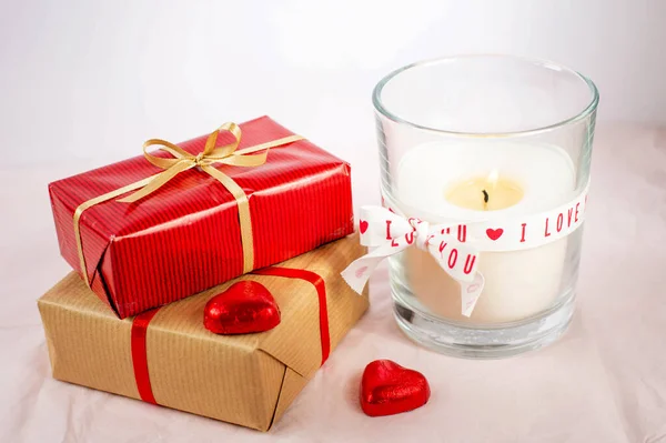 Tematem Walentynki Płonąca Świeca Dwa Czerwone Cukierki Kształcie Serc Pakowane — Zdjęcie stockowe