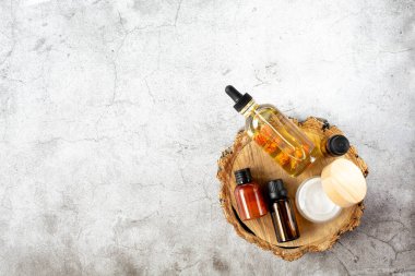 Kaplıca ve güzellik. Bir takım kozmetik ürünleri, çiçek tomurcukları ve kremalı bir şişe doğal yağ gri arka planda bir ahşap tezgahta bulunur. Metin için boş alan. Yukarıdan görüntüle.