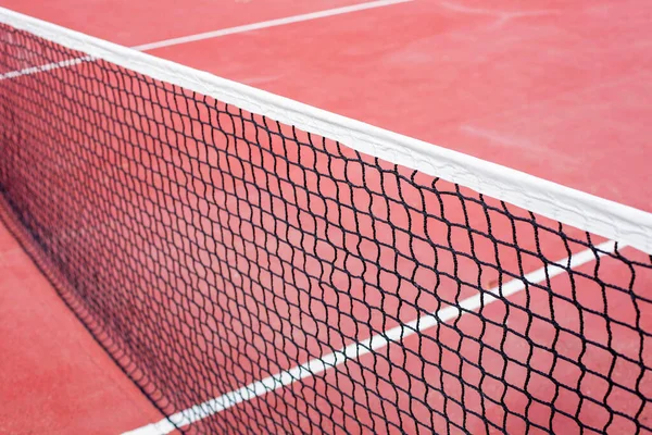The tennis net on the background of the court is red. The theme of sports and a healthy lifestyle. Close-up image.