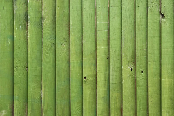 The background of the boards is painted green. Wooden green fence.