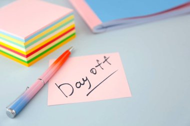 Yazılı notlar için kâğıt - izin günü, masada bir panelin ve ofis malzemelerinin yanında.. 