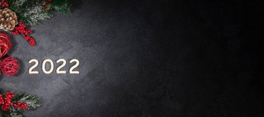 Mutlu yıllar 2022, Yeni Yıl, köknar dalları ve kırmızı Noel toplarıyla süslenmiş karanlık arka plan