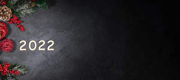 Mutlu yıllar 2022, Yeni Yıl, köknar dalları ve kırmızı Noel toplarıyla süslenmiş karanlık arka plan