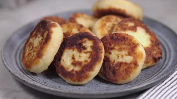 Mão leva uma panqueca de coalhada, porção de pedaços de queijo cottage caseiro ou syrniki no prato, close-up — Vídeo de Stock