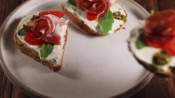 Woman hand puts ham cheese sandwich on plate, ready to eat bruschetta, close up — Stock Video