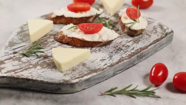 Listo para comer sándwiches caseros con queso cottage, tomates cherry y romero en el tablero de madera gris zoom in — Vídeo de stock