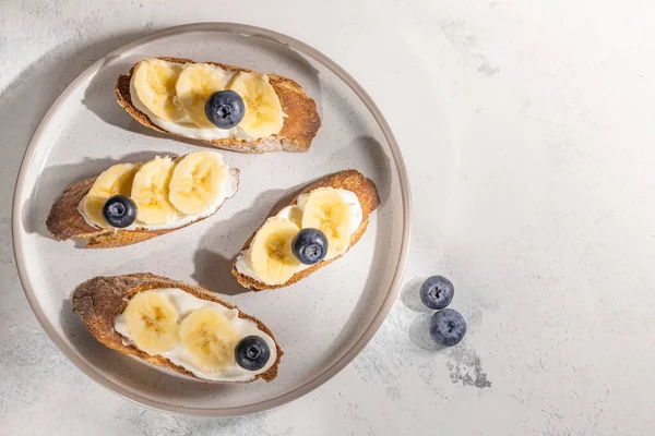 Банановые сэндвичи с черникой на тарелке, здоровый завтрак, еда на сером фоне с бесплатным местом для текста — стоковое фото
