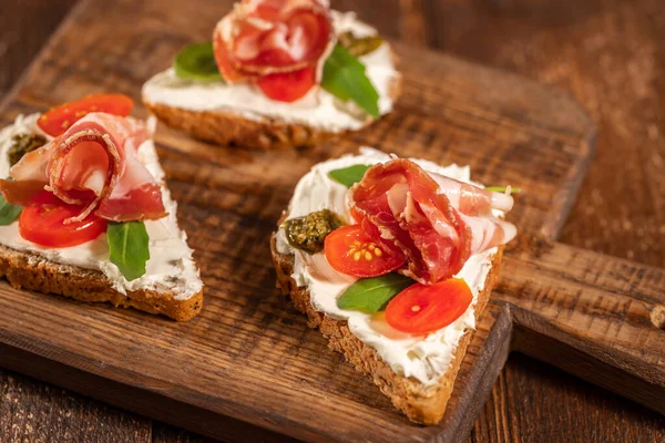 Peynirli tost, jambon ve ahşap tahtada yeşillik ve ahşap arka planda.
