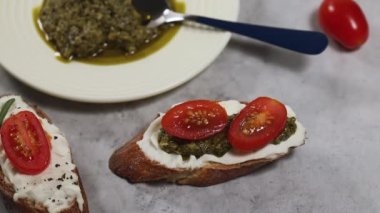 Evde sandviçler pişirmek, sebzeleri süzme peynir ve pesto soslu dilimlenmiş ekmeğe koymak.