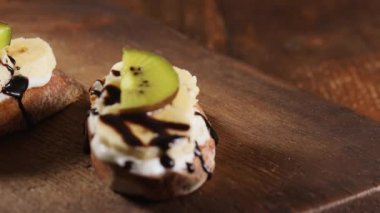 Kadın eli tahtanın üzerine kivili sandviç koyar, ev yapımı sandviçleri yemeye hazır, ev yapımı meyve tatlısı konsepti.