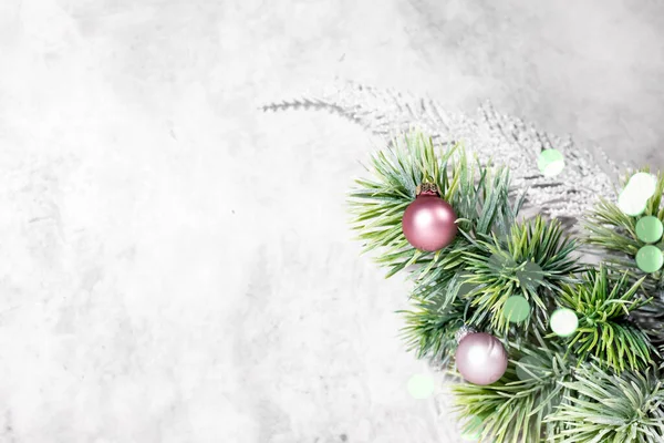 Conceito de cartão de Natal ou Ano Novo, decoração de bugigangas rosa, ramo de abeto verde, bandeira cinza com bokeh, espaço livre para texto — Fotografia de Stock
