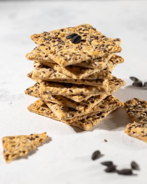 Ayçiçeği tohumlu bisküvi yığını ve beyaz arka planda susam, dikey, seçici odak