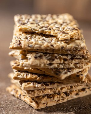 Stack of biscuit crackers with sunflowers seeds and sesame, vertical, close up, selective focus