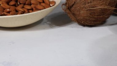 White sweet coconut candies in plate, coconuts and almond nuts, ingredients on background