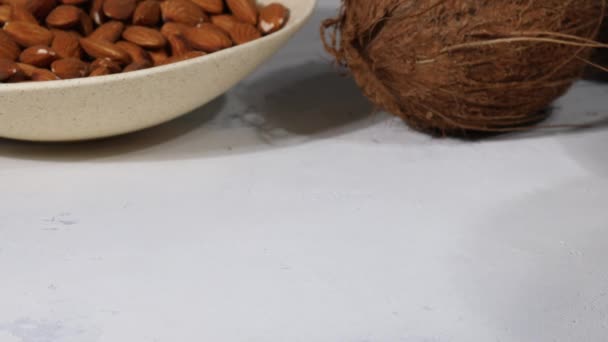 White sweet coconut candies in plate, coconuts and almond nuts, ingredients on background — Video Stock