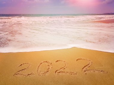 2022 sayıları, kumlu sahilde denizin, okyanusun arka planında yazılı. Mutlu yıllar ve tatiller.!