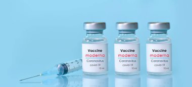 Harkiv. Ukrayna. 9 Ocak 2021. Şırınga, mavi arka planda Moderna logosu olan üç şişe Coronavirus aşısı. Tıp, sağlık konsepti. Ders için yer ayır.