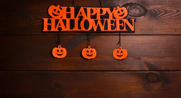Happy Halloween written on a Happy Halloween written on a signboard with pumpkins on a Wooden Background .