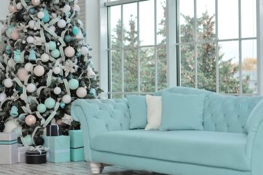 Noel ağacıyla süslenmiş bir Noel odası, pencerenin yanında bir kanepe..