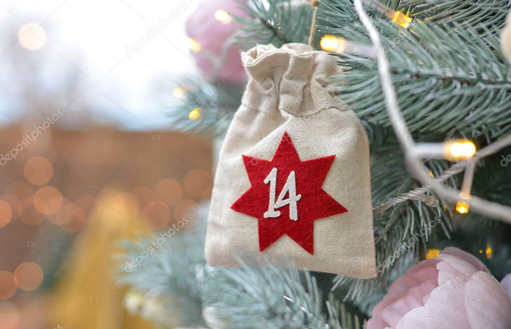 Christmas background. Advent calendar in the form of an eco bags hanging on a beautifully decorated christmas tree.Christmas gifts and tasks